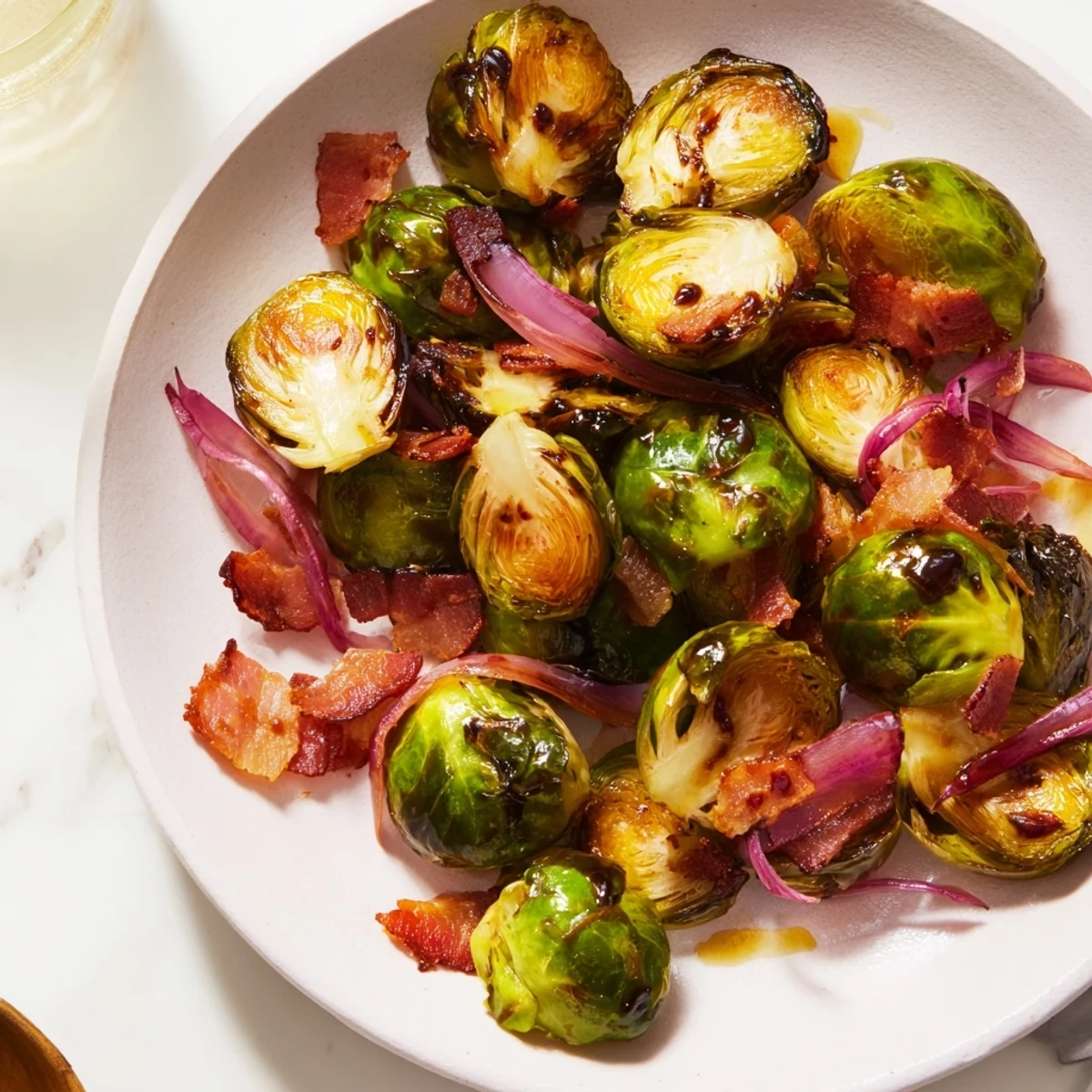 Roasted Brussels Sprouts with Crispy Turkey Bacon tossed with red onion and garlic powder, plated.