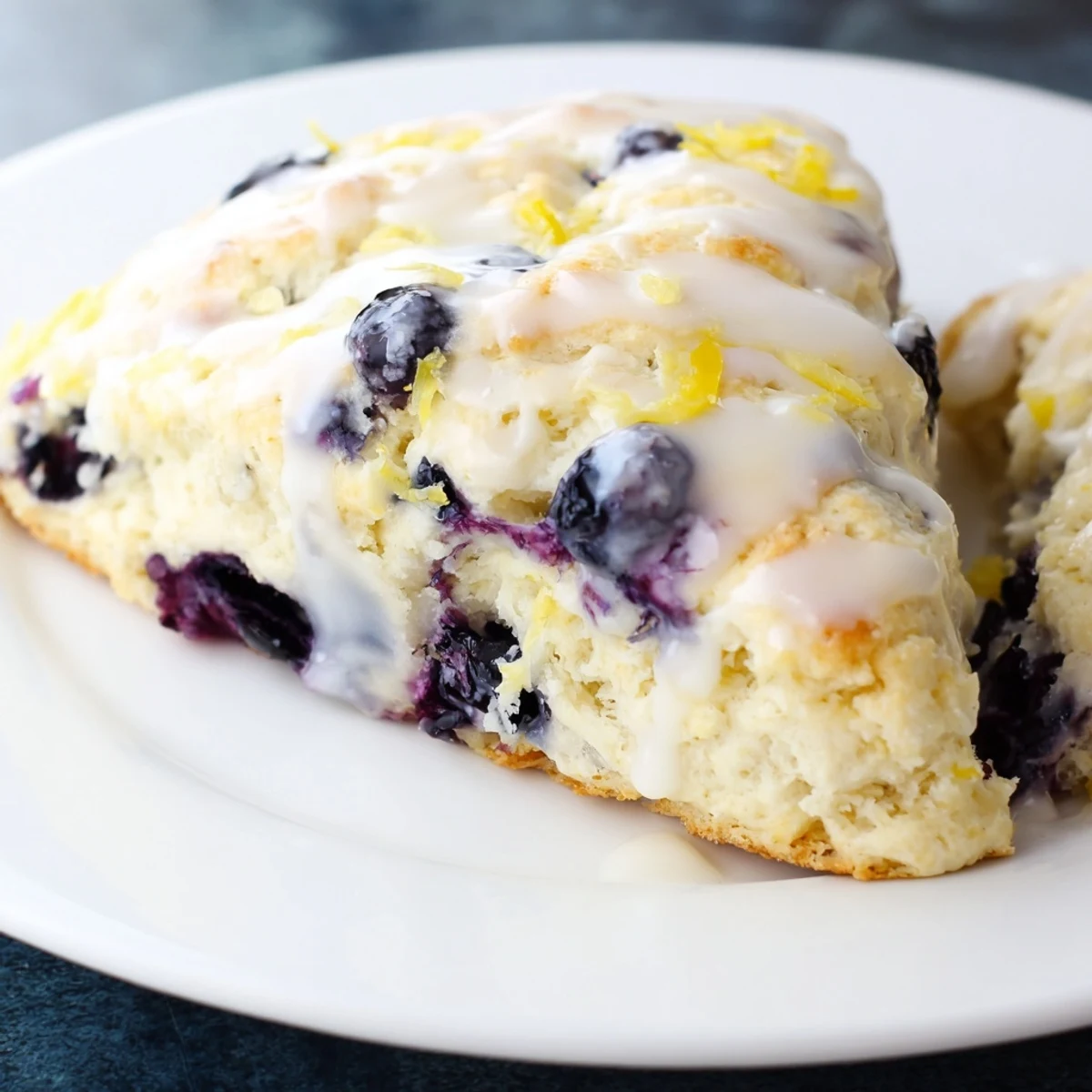 Freshly baked Lemon Blueberry Scones with Sweet Vanilla Glaze on a cooling rack, topped with sweet glaze drips.