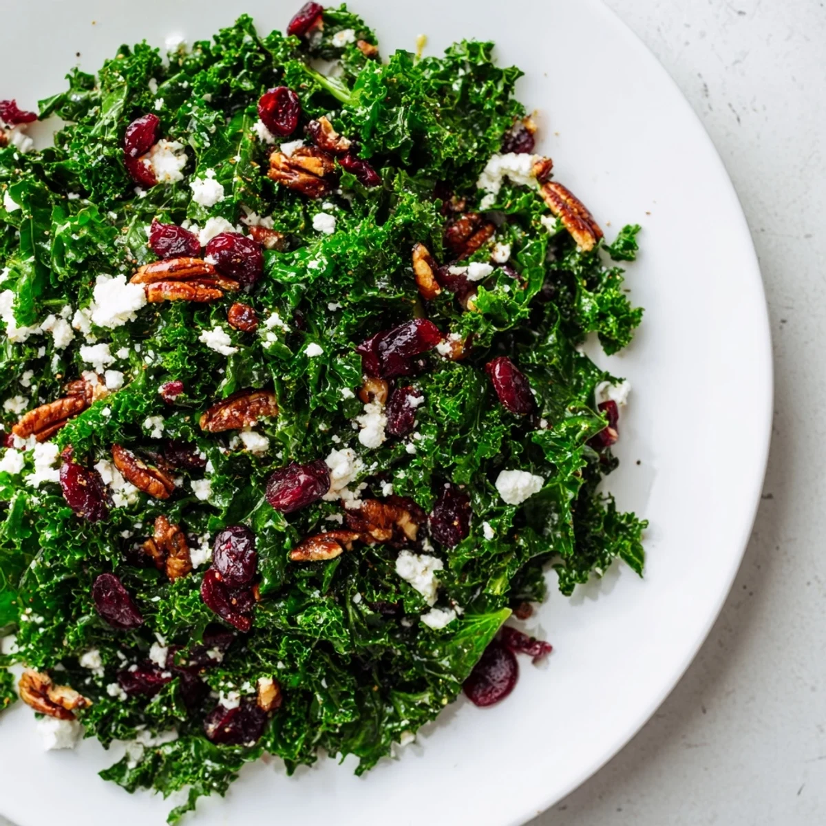 Golden toasted pecans and ruby cranberries shine atop tender massaged kale in this hearty Winter Kale Salad with goat cheese.