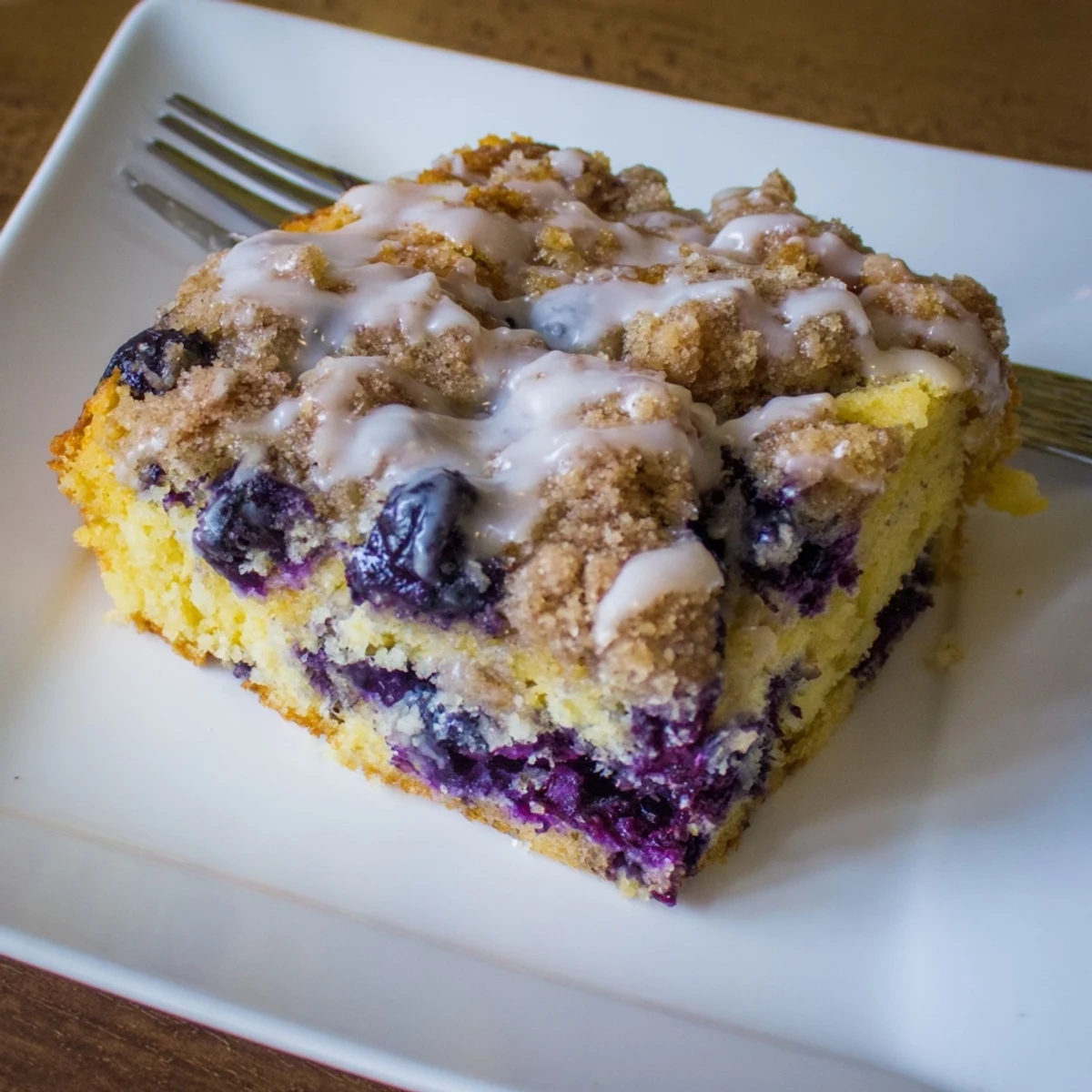 A close-up of Lemon Blueberry Coffee Cake showcasing tender yellow cake with bright blueberries and a rustic, cinnamon-spiced streusel topping.