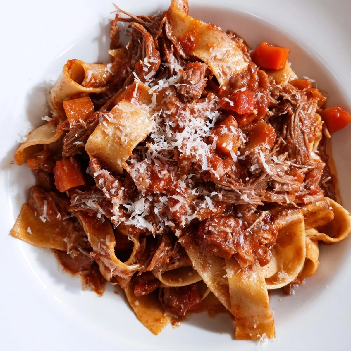 A hearty Italian-inspired beef ragu with deep tomato aroma, served alongside a glass of red wine for a cozy meal.