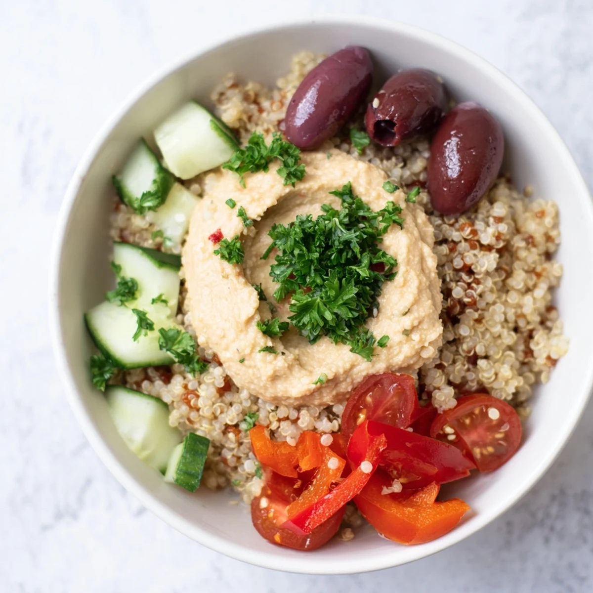Vibrant Mediterranean Quinoa Bowl with kalamata olives, cherry tomatoes, and roasted red peppers, served with lemon wedges for a gluten-free meal.