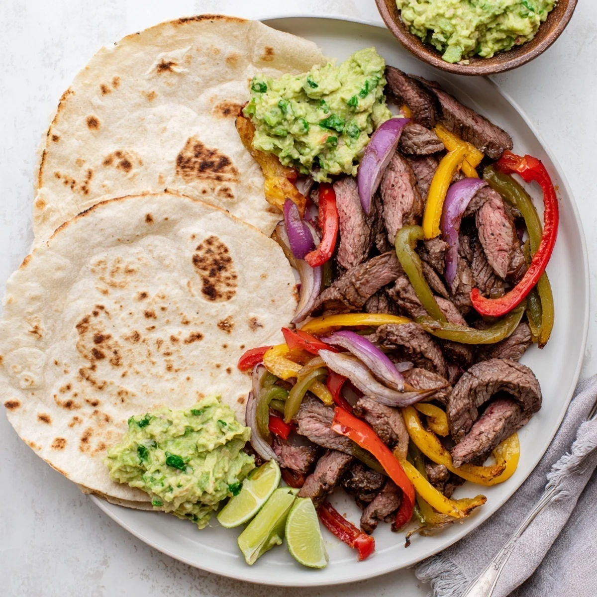 Freshly prepared Beef Fajitas with Guacamole, featuring juicy seared steak, sautéed peppers, and ripe avocado slices ready for wrapping.