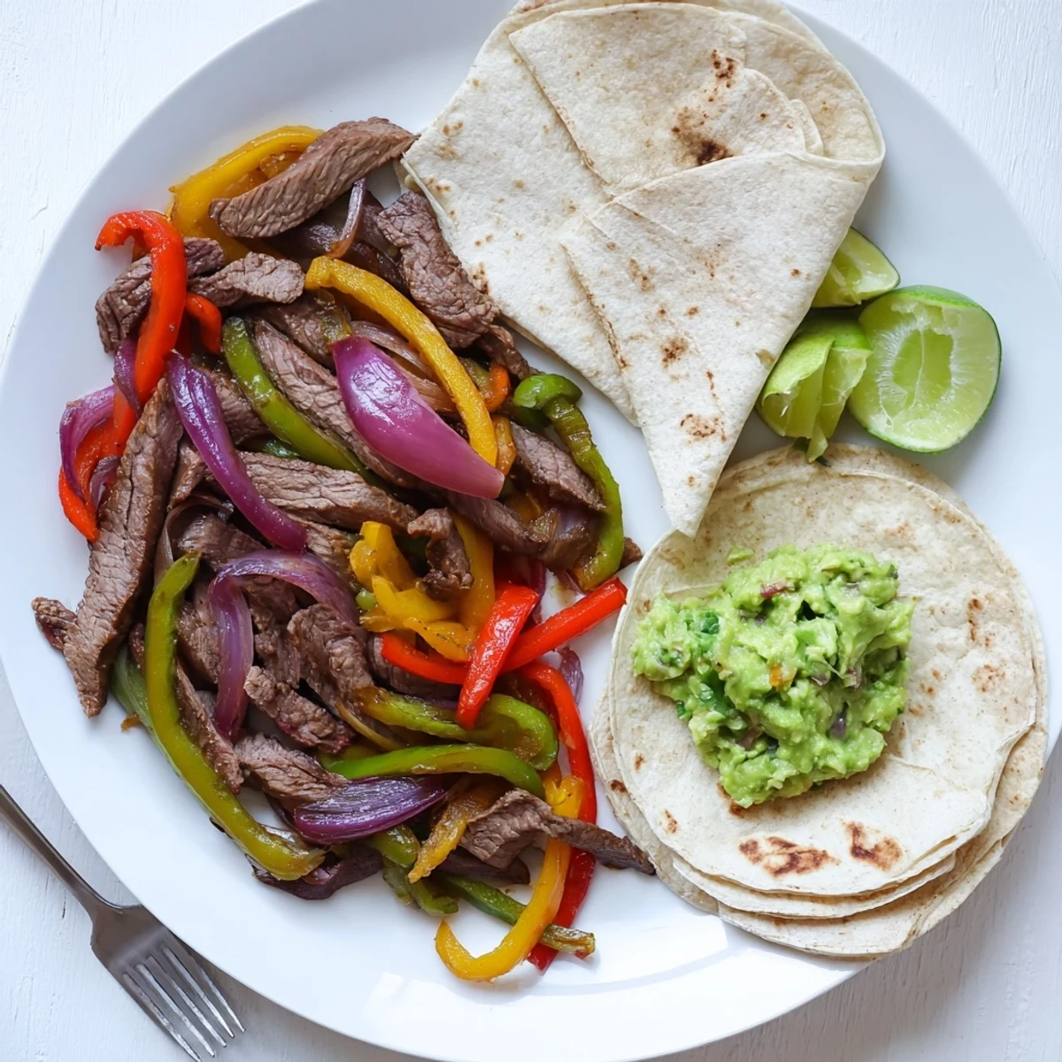 Golden tortillas filled with sizzling Beef Fajitas and guacamole, garnished with lime wedges and cilantro for a vibrant Tex-Mex meal.