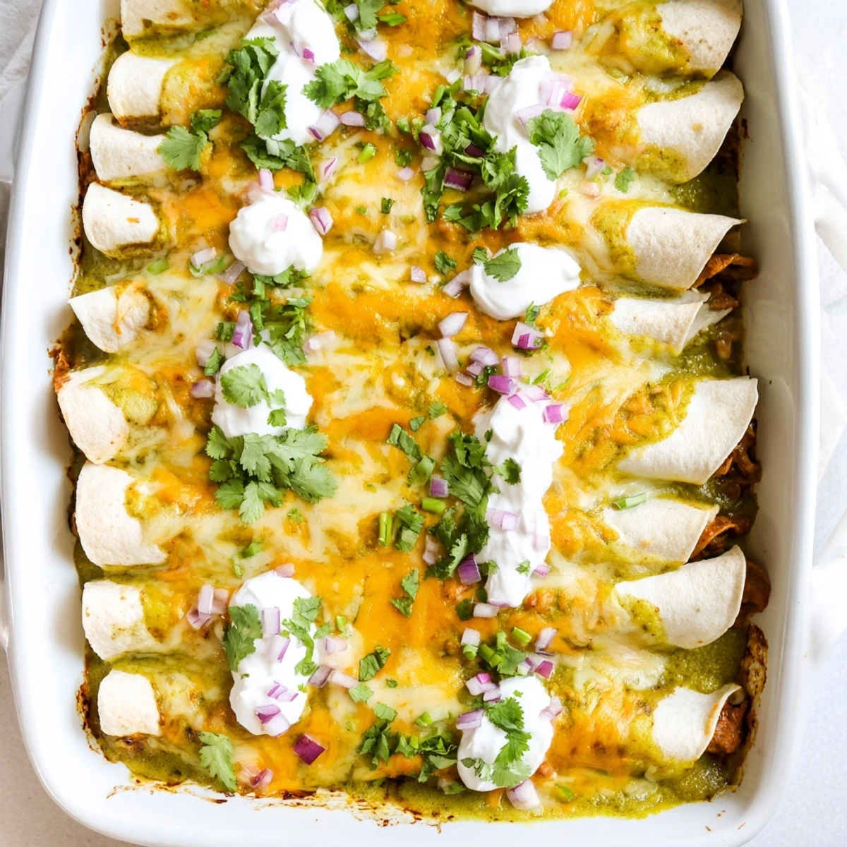 Homemade Beef Enchiladas with Green Sauce presented in a baking dish, cheese bubbling golden-brown, with a side of Mexican rice and refried beans for a complete meal.