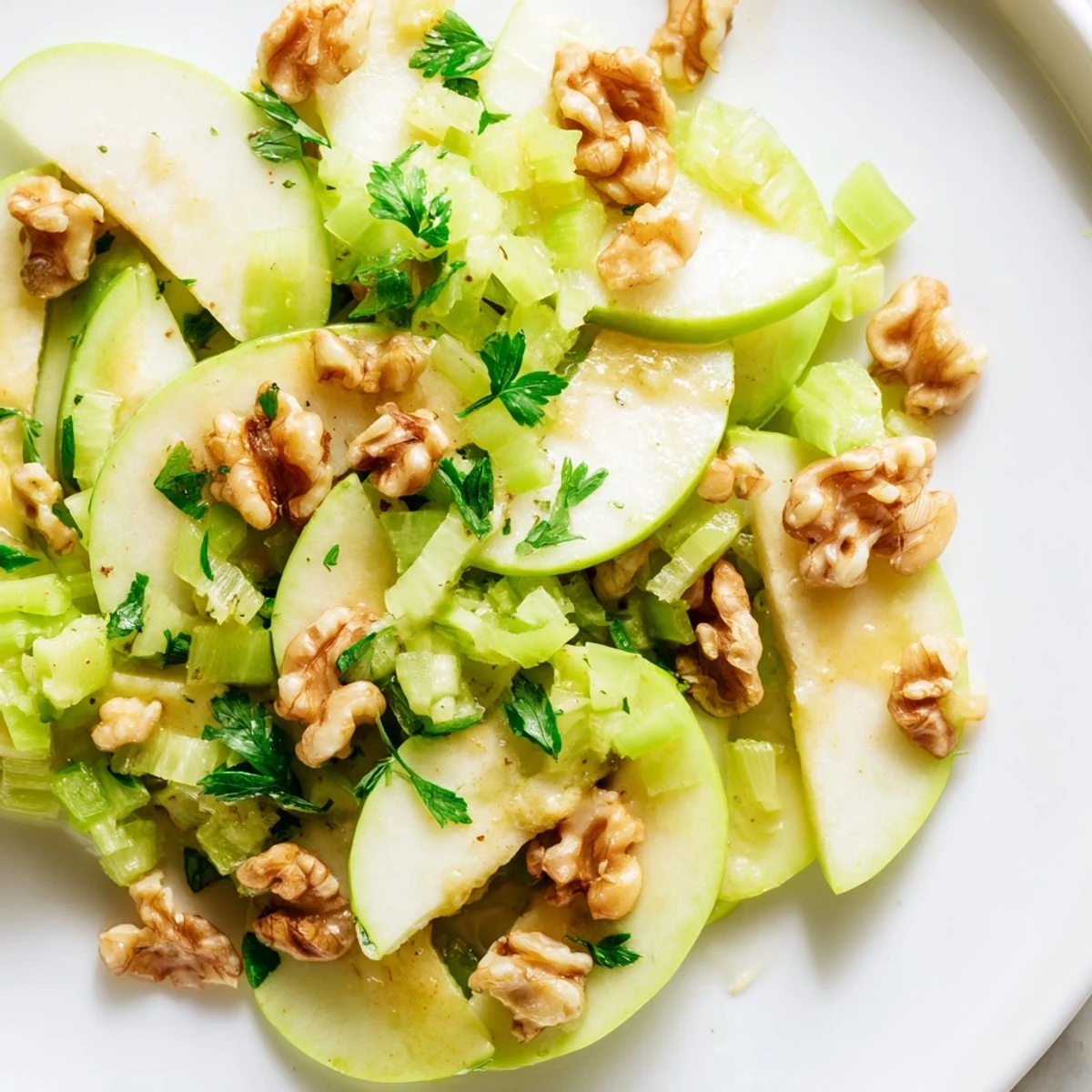 Vibrant green apple and celery salad drizzled with tangy lemon-honey dressing, perfect alongside grilled chicken for a light meal.