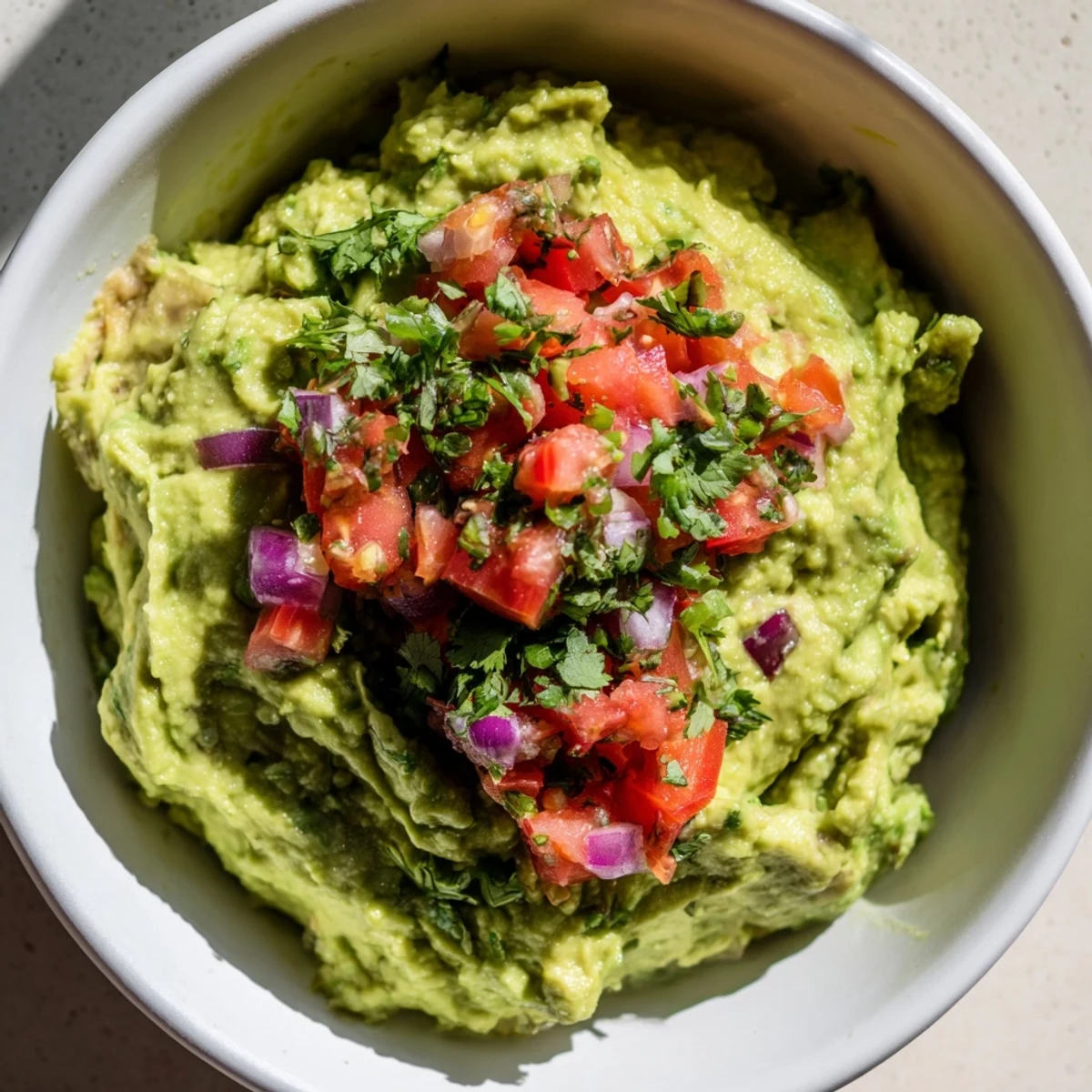 Fresh, chunky Game Day Guacamole with Salsa piled high in a serving bowl, surrounded by crispy tortilla chips ready for dipping at a party.