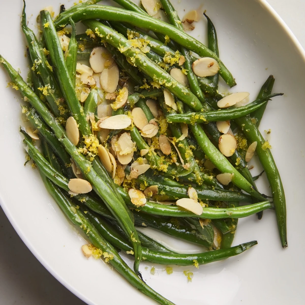 Tender green beans with lemon and toasted almonds sautéed in garlic butter, piled high in a serving bowl.