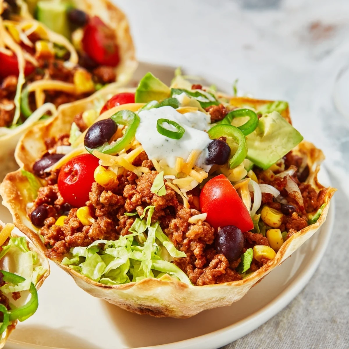 Crispy homemade tortilla bowl filled with seasoned ground beef, black beans, corn, avocado, and cheddar for a hearty Tex-Mex meal.
