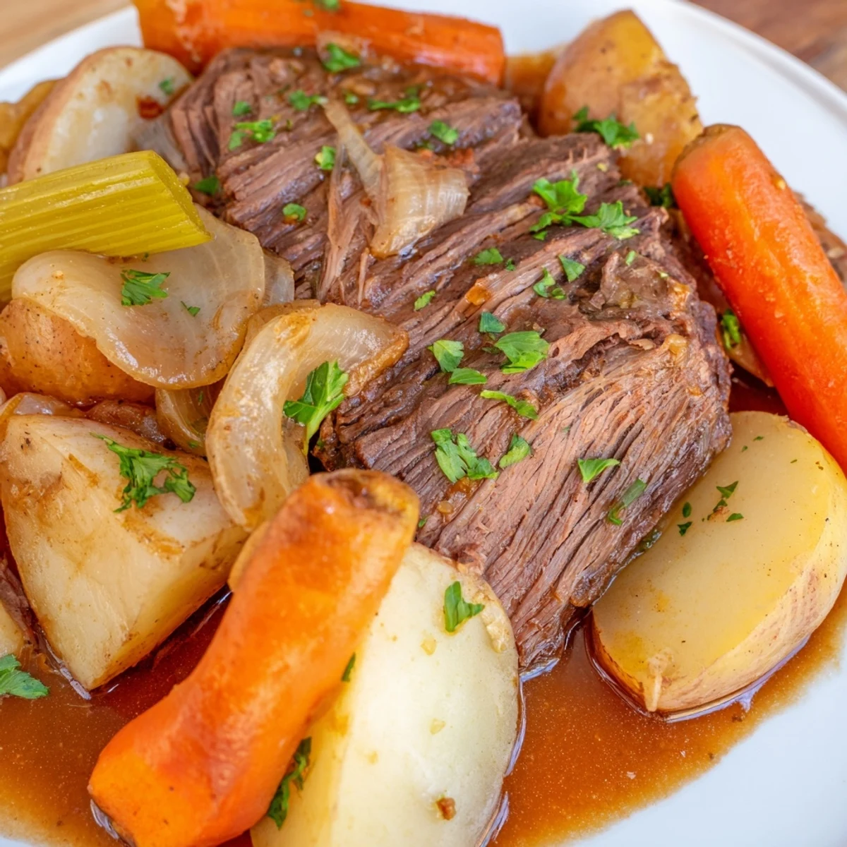 A close-up of Slow Cooker Beef Pot Roast with Root Veggies on a rustic platter, featuring tender beef and glossy carrots. 