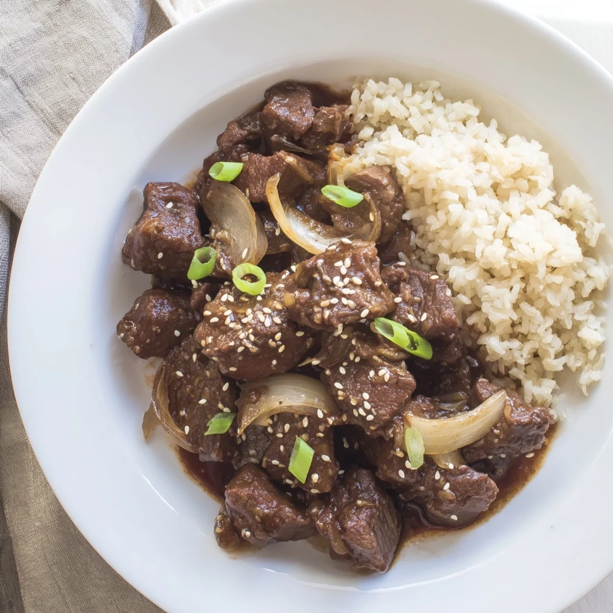 A bowl of Crock Pot Korean Beef garnished with green onions and sesame seeds, perfect for easy weeknight dinners.