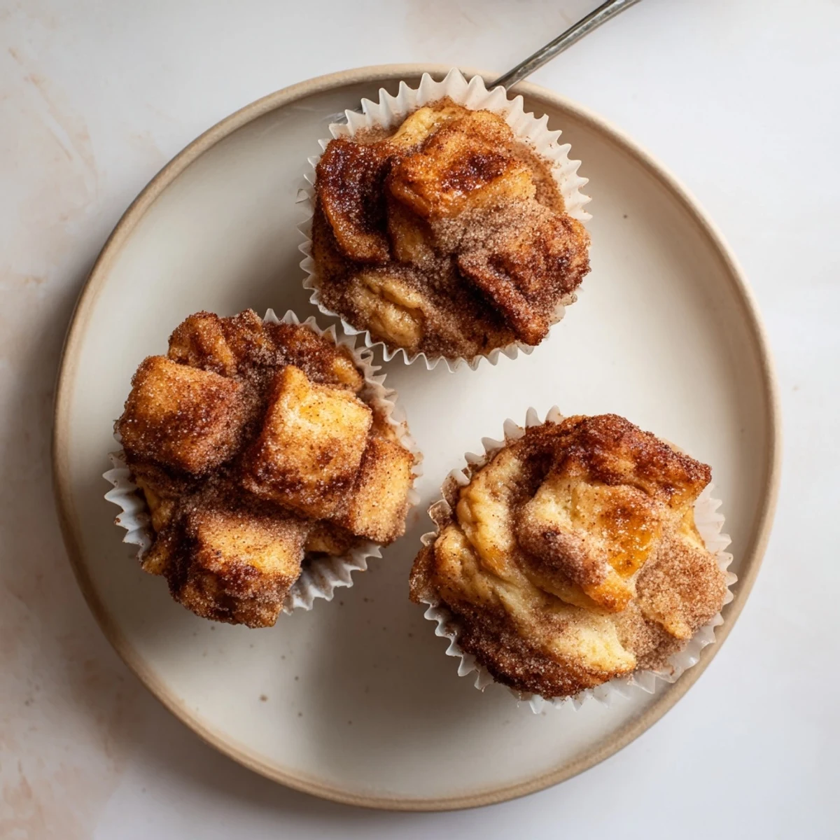 Warm Cinnamon Sugar French Toast Muffins are served on a white plate with fresh berries nearby.
