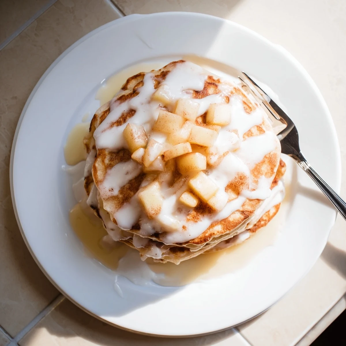 Warm Apple Fritter Pancakes stacked high, drizzled with glaze and served alongside a bowl of fresh berries and syrup.