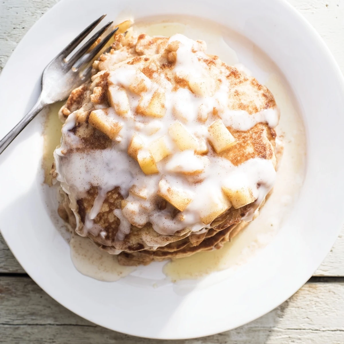 Golden-brown Apple Fritter Pancakes topped with sweet glaze, paired with a fresh cup of coffee on a sunny breakfast table.