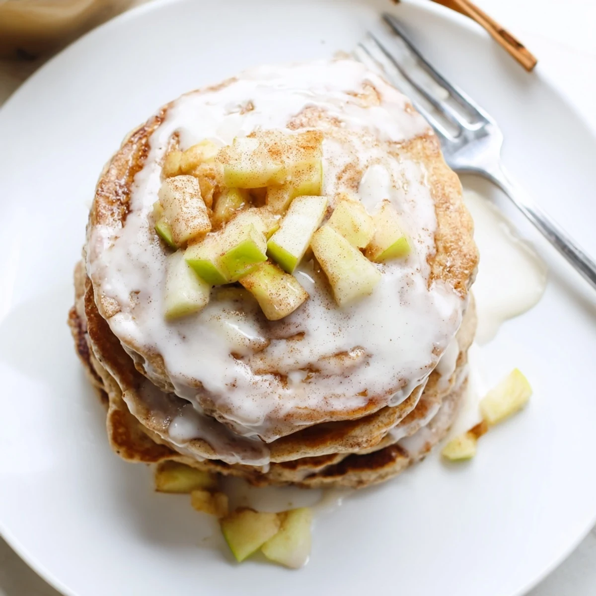 Fluffy Apple Fritter Pancakes with diced apples and cinnamon, resting on a white plate ready for a cozy brunch serving.