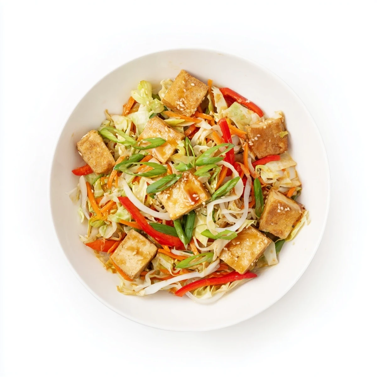 A serving bowl of colorful Stir Fried Tofu and Cabbage, garnished with fresh green onions, ready to be eaten with rice.
