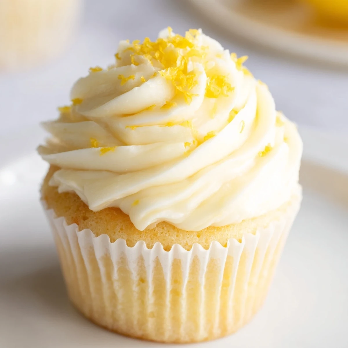 Limoncello Cupcakes with fluffy lemon buttercream and a sprinkle of zest for a sweet summer treat.