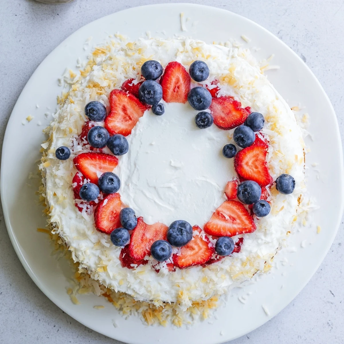 Moist layers of Pineapple Coconut God Bless America Cake with cream cheese frosting and berries.