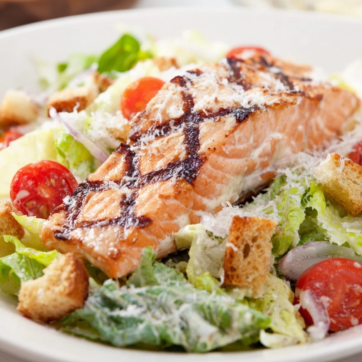 Flaky salmon Caesar salad drizzled with creamy homemade dressing and sprinkled with grated Parmesan