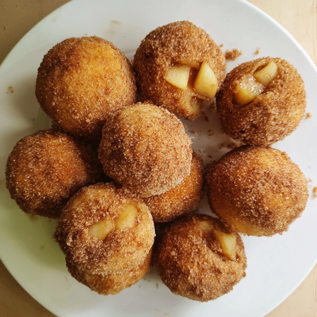 Golden caramel apple pie bombs with cinnamon sugar coating on a baking sheet