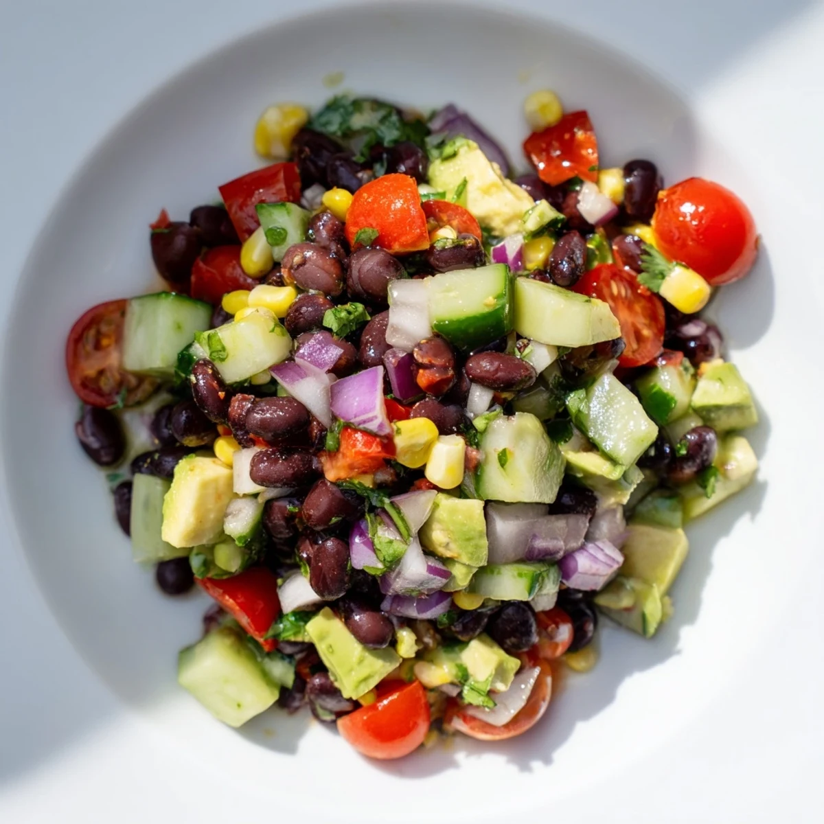 Fresh chopped black bean salad featuring vibrant red peppers, tomatoes, and creamy avocado cubes