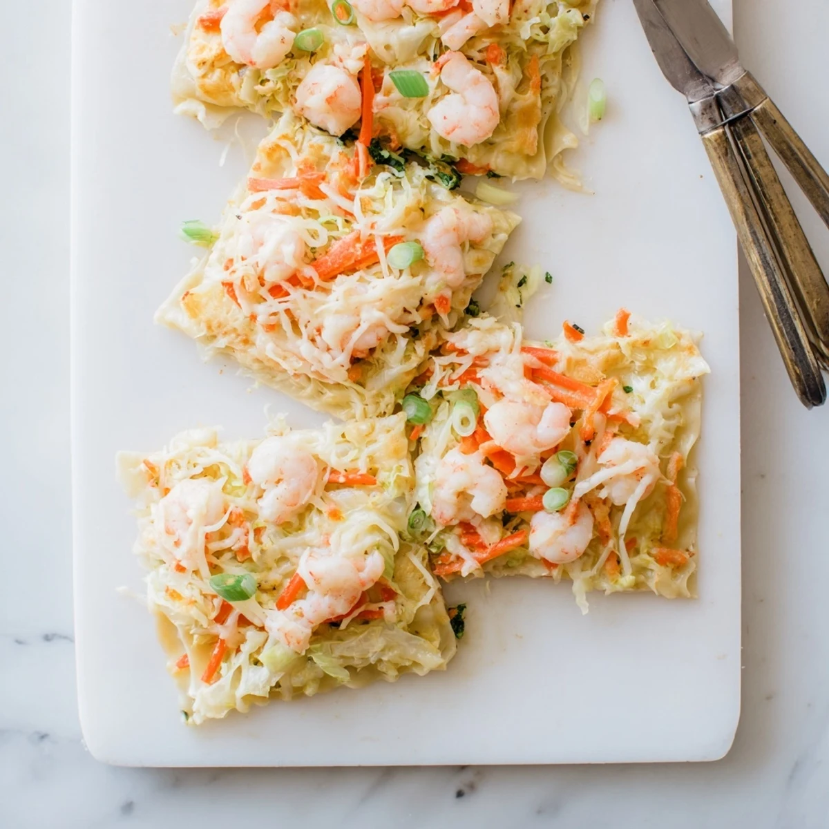 Baked shrimp dumpling lasagna square with golden brown mozzarella and fresh scallion garnish