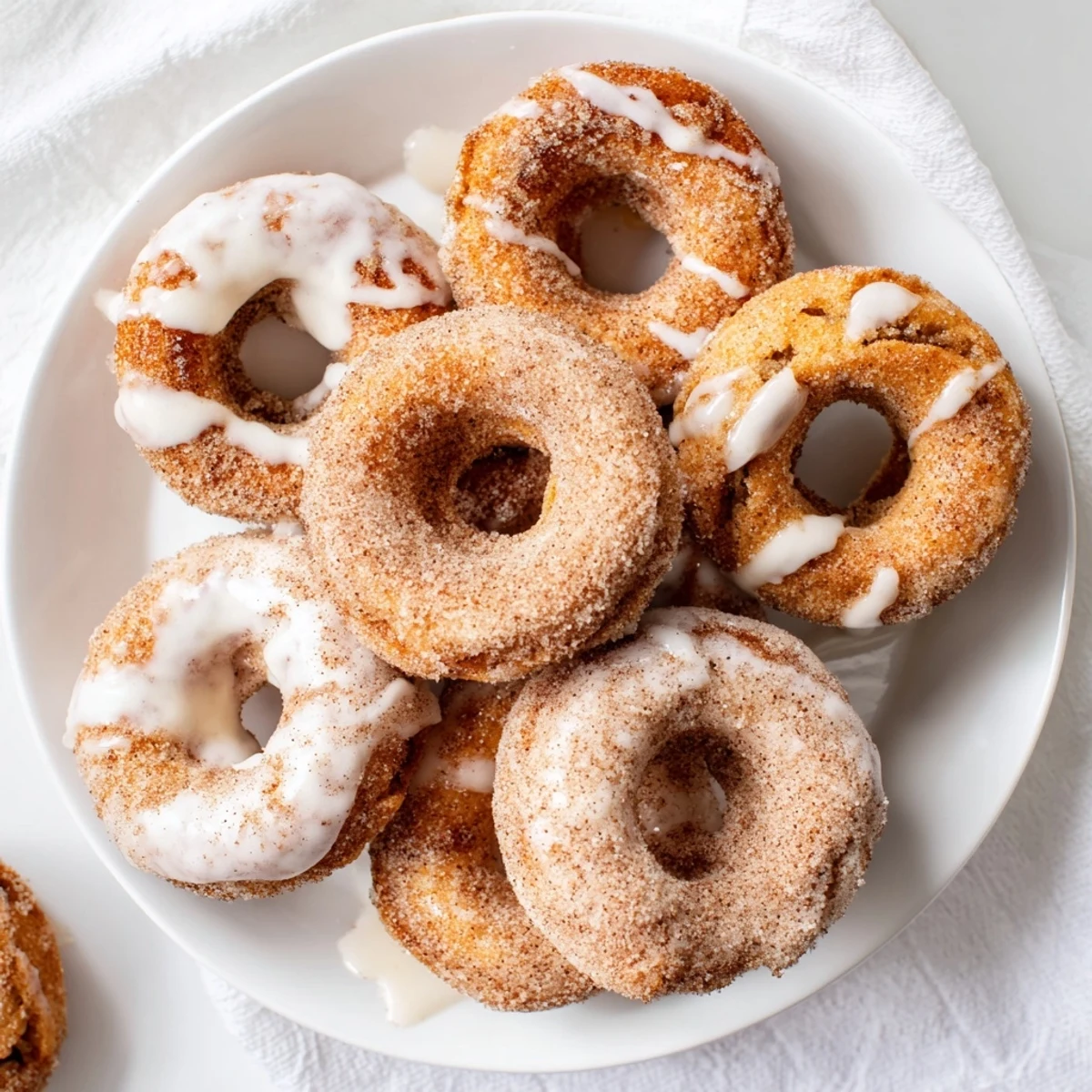Golden brown pumpkin spice biscuit donuts with sweet glaze drizzle on a white plate