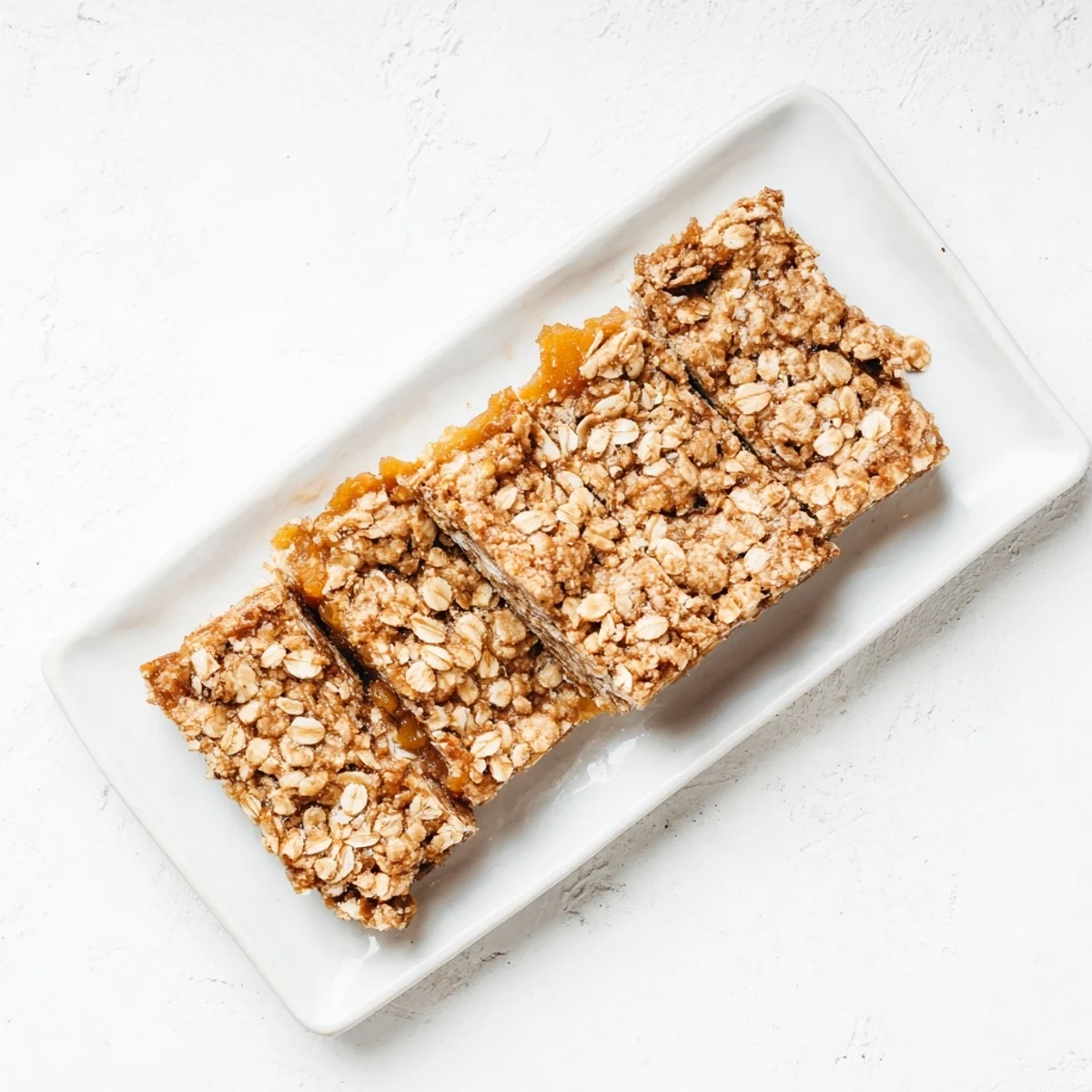 Chewy gluten-free oatmeal apricot bars featuring tender dried apricots layered between buttery oat crumble on a white plate