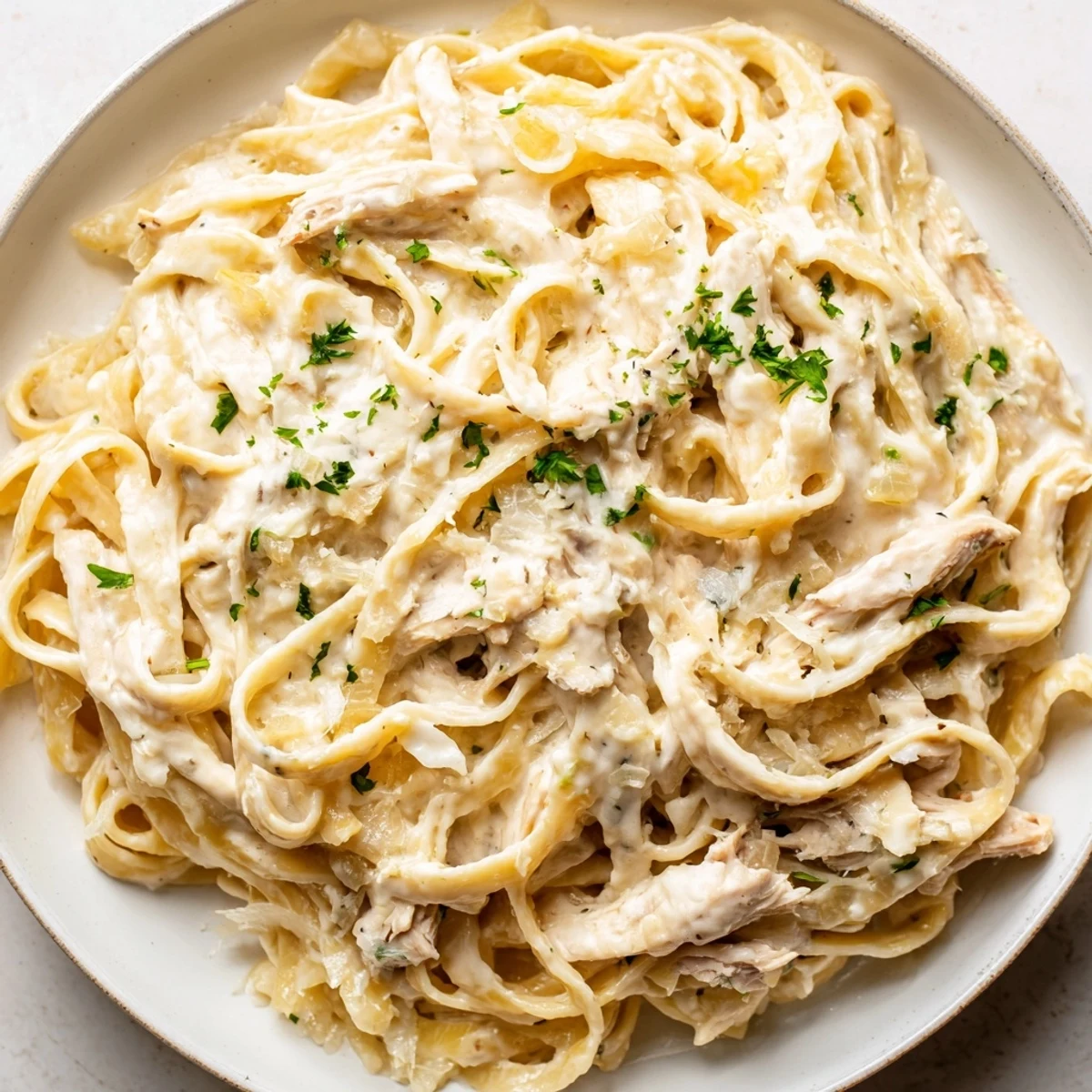 Creamy Crock Pot Chicken Alfredo with tender shredded pasta and rich parmesan sauce in a white bowl