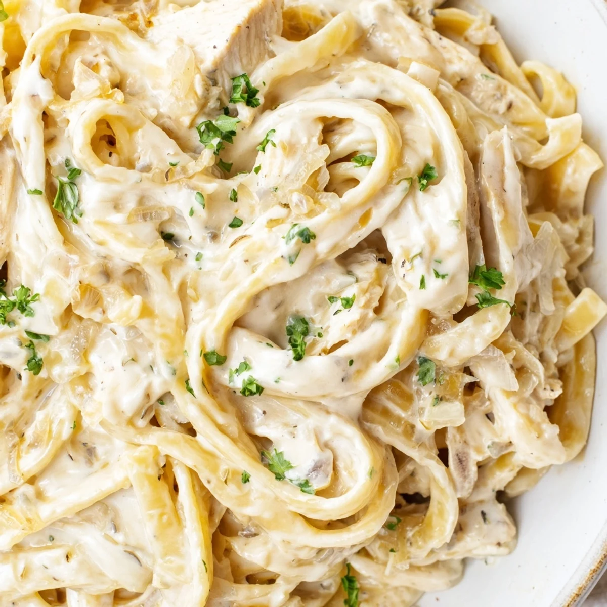 Slow cooker Chicken Alfredo featuring fettuccine coated in velvety garlic cream sauce with shredded chicken breast