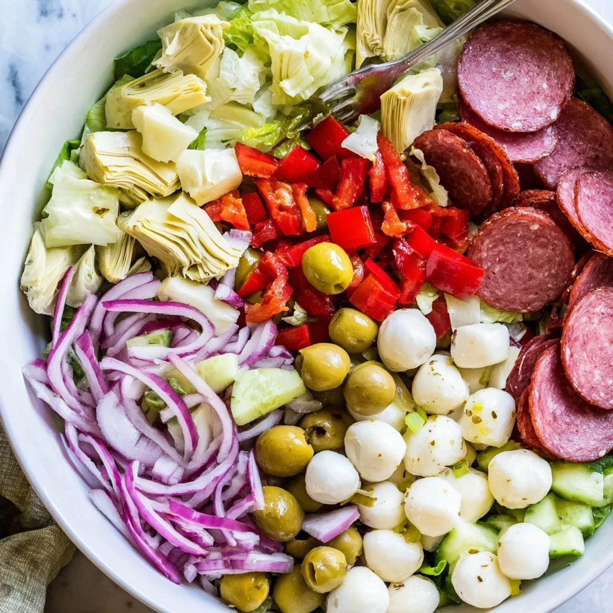 Vibrant Italian antipasti salad featuring crisp romaine, artichokes, roasted peppers, and tangy dressing