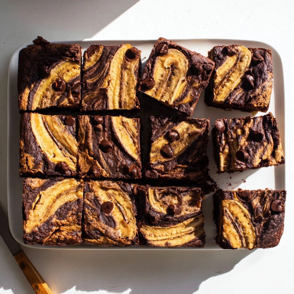 Sliced squares revealing the marble pattern of chocolate brownie and banana bread layers on a white plate