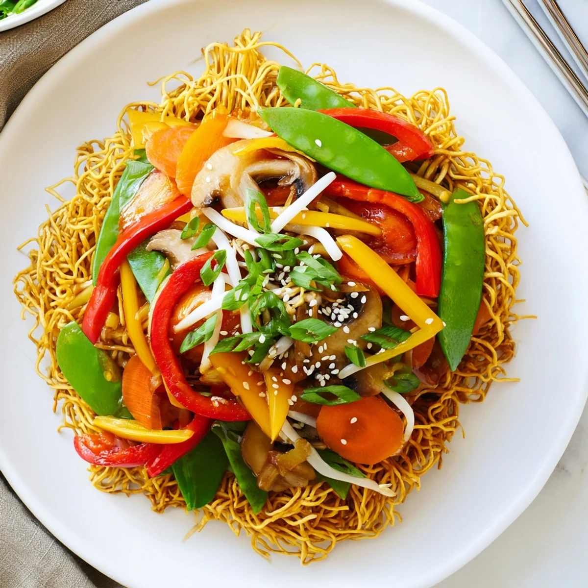 Golden crispy noodle chow mein topped with colorful stir-fried vegetables and savory sauce