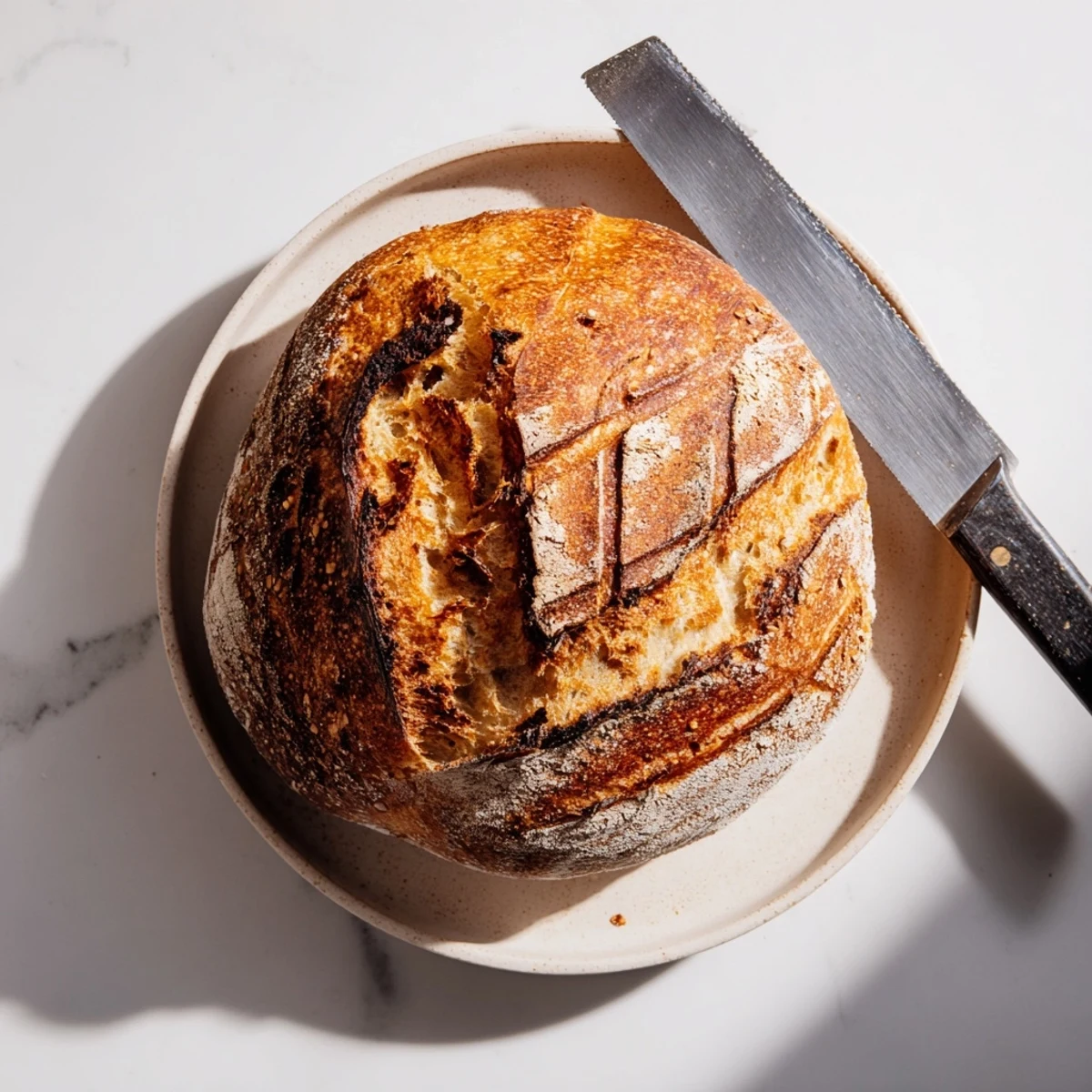 Golden brown sourdough bread with crispy crust and airy interior, sliced on wooden board
