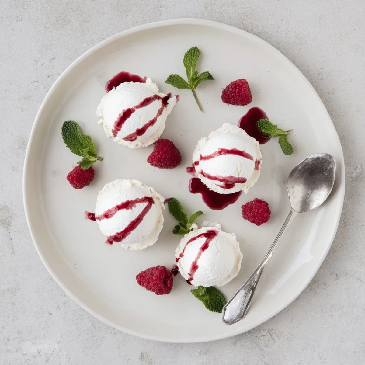 Bite-sized Pavlova bombs topped with fluffy whipped cream and tangy raspberry sauce