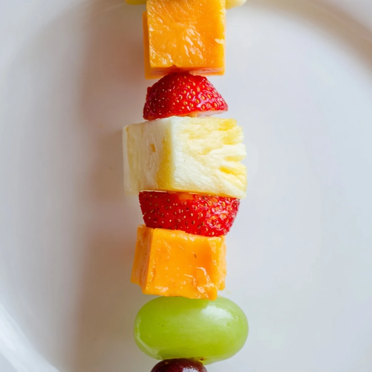Colorful fruit and cheese kabobs arranged on platter with fresh mint garnish
