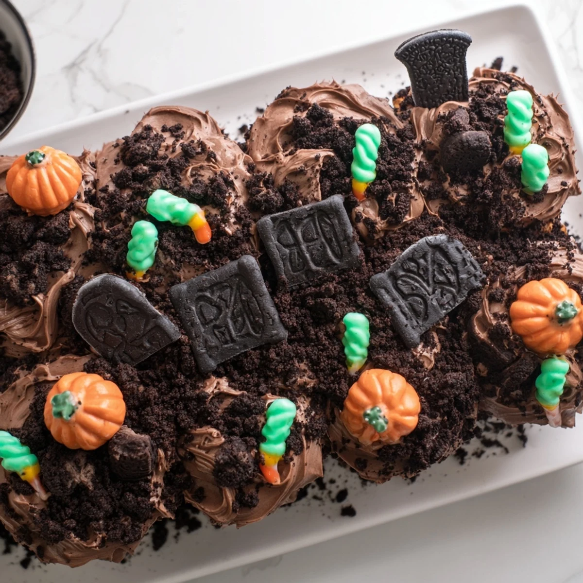 Pull Apart Graveyard Cupcakes arranged on a tray with chocolate frosting and cookie crumb dirt