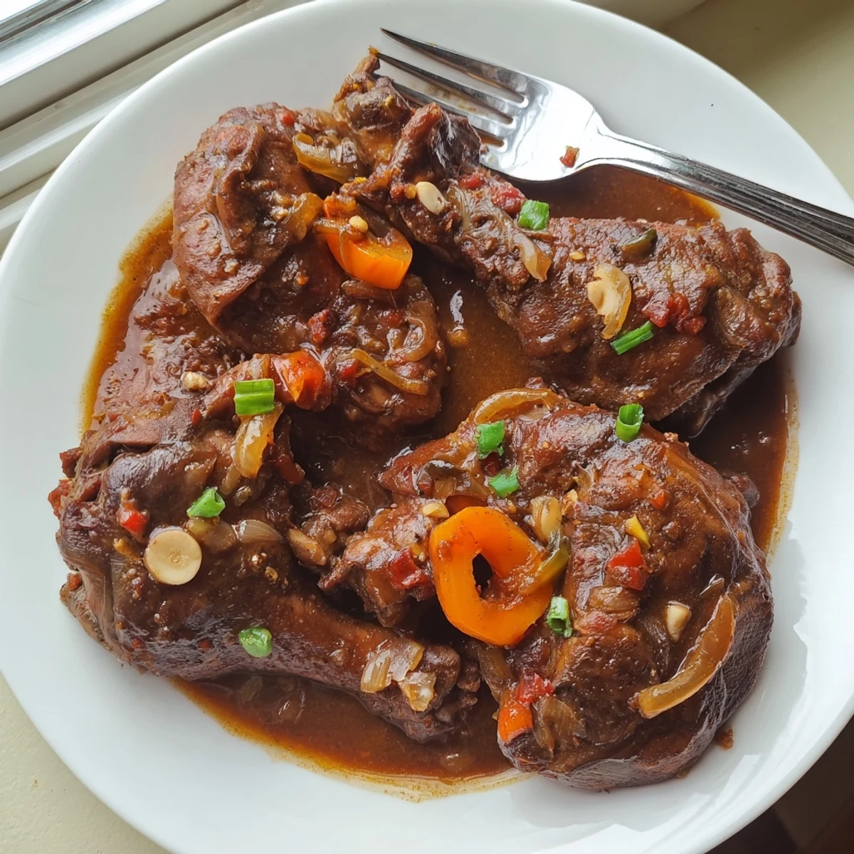 Golden seared Jamaican brown stew chicken simmered in a rich spiced gravy