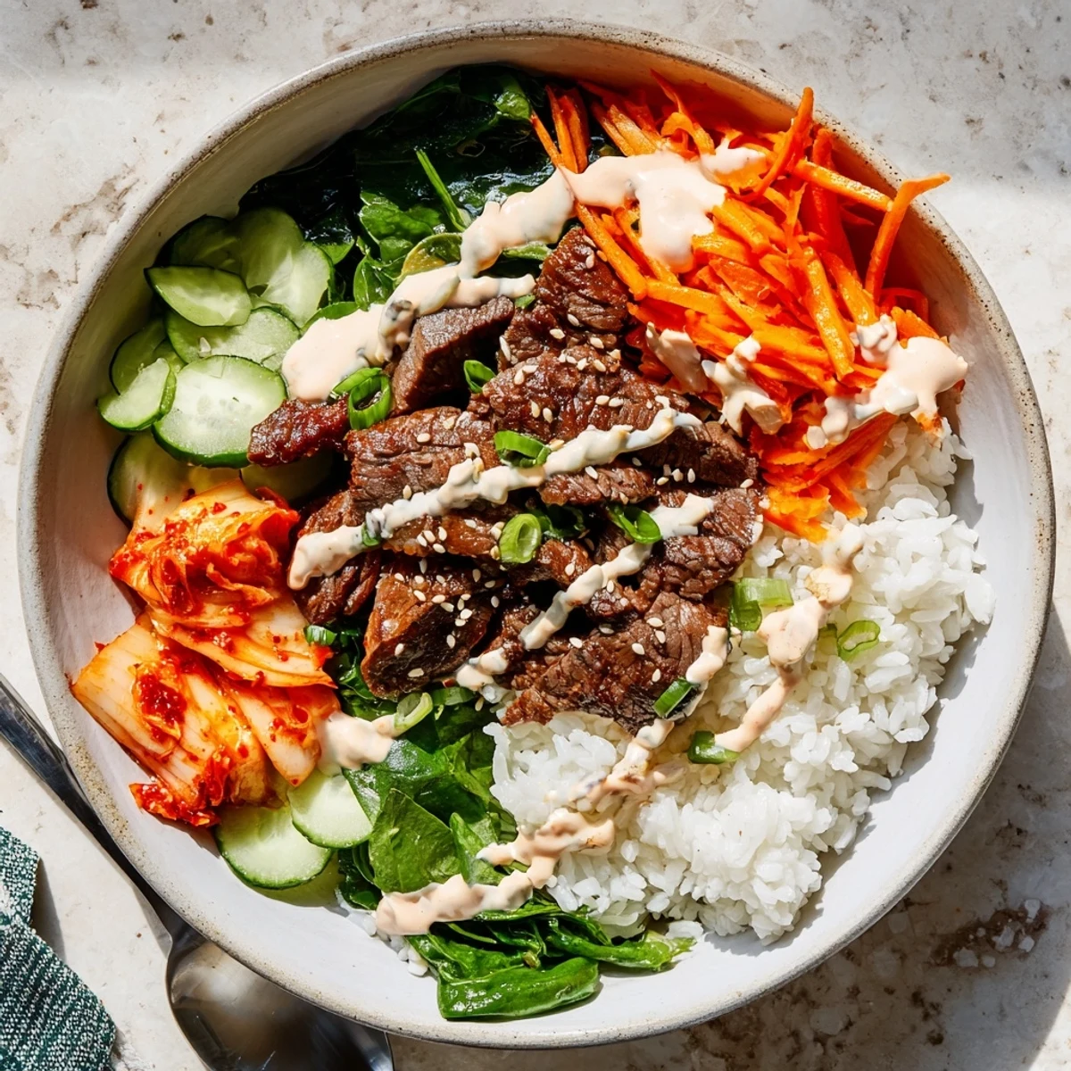 Korean BBQ steak rice bowls drizzled with creamy spicy sauce and crisp veggies