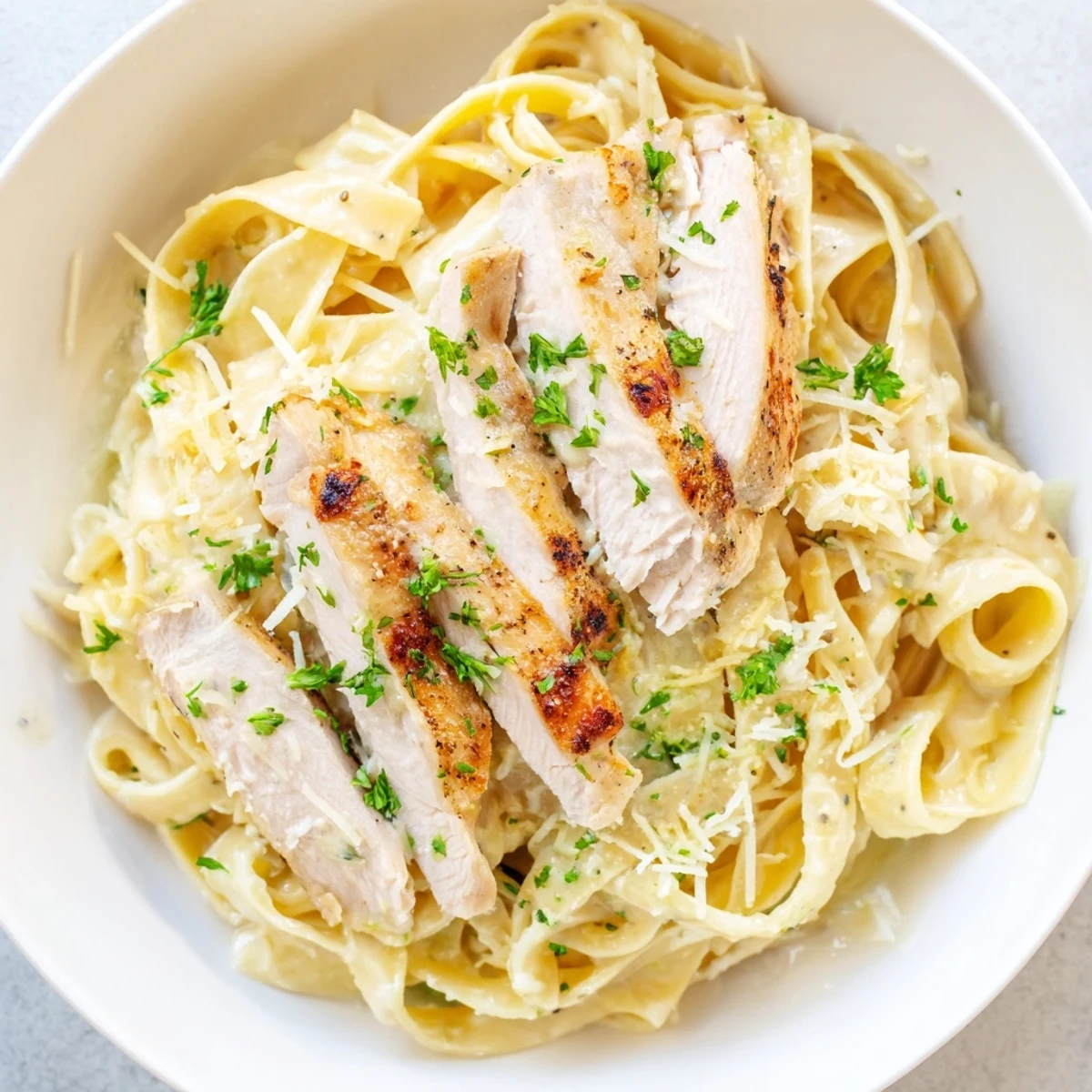 Creamy Garlic Chicken Pasta with sliced golden chicken, luscious sauce, parsley garnish