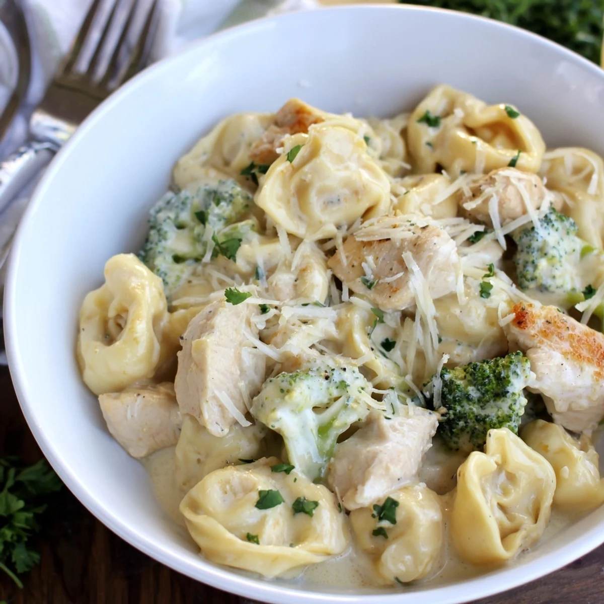 A bowl of Creamy Garlic Parmesan Tortellini Chicken Broccoli Recipe, rich, cheesy sauce