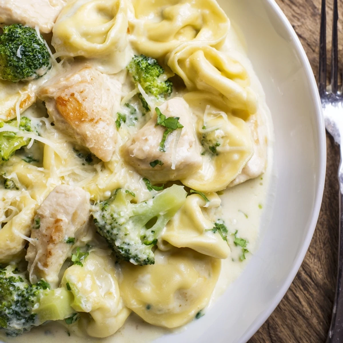 Creamy Garlic Parmesan Tortellini Chicken Broccoli Recipe plated beside crusty bread and extra Parmesan
