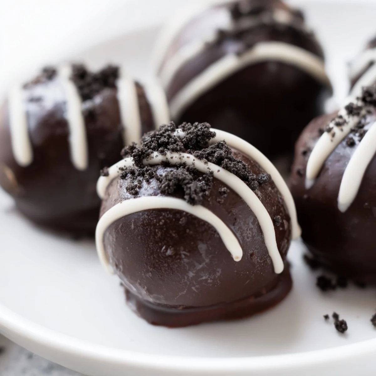 Homemade mint Oreo truffles arranged on a white serving plate with green drizzles