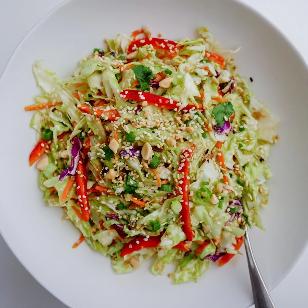 Bowl of Asian Cabbage Salad, crisp strands, topped with chopped peanuts and cilantro