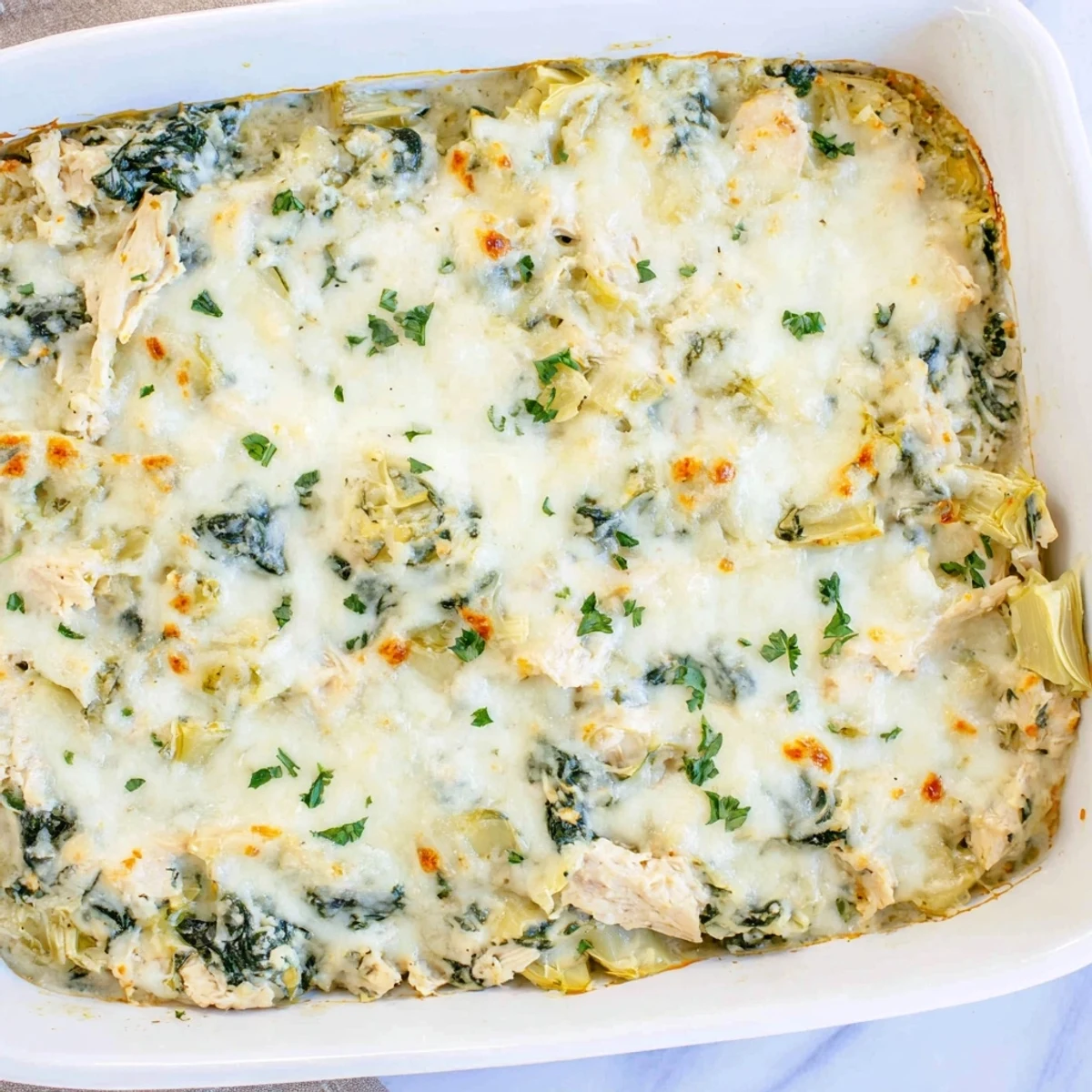 Baked spinach artichoke chicken casserole topped with golden melted cheese