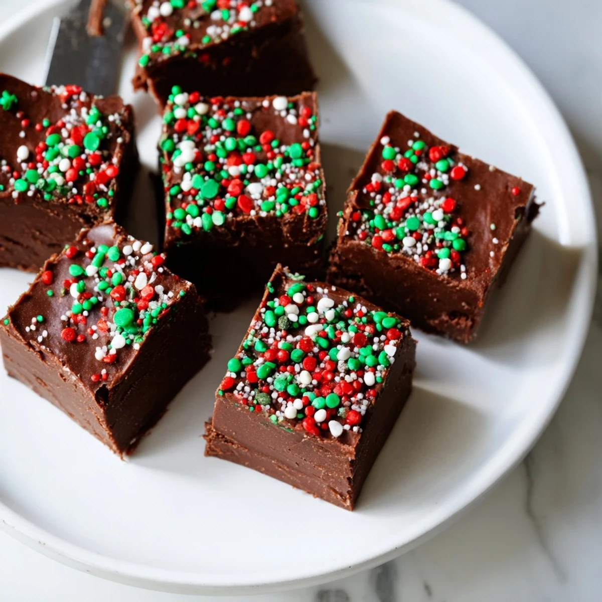 Creamy Christmas fudge with sprinkles cut into neat squares on a rustic cutting board
