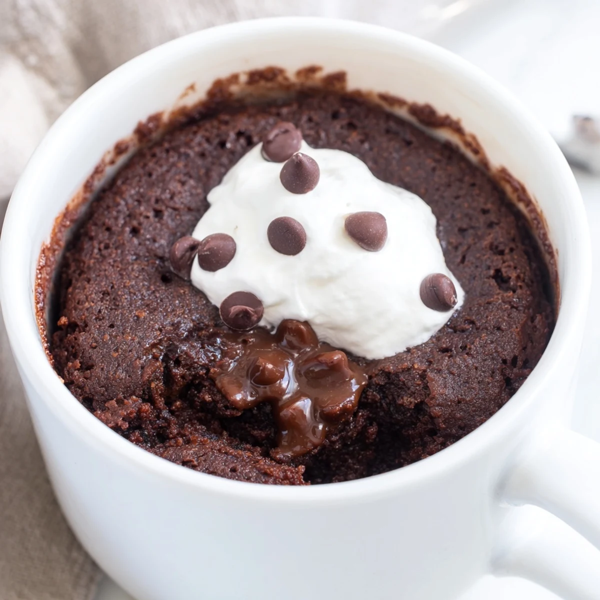 Fudgy gluten free chocolate mug cake with glossy cocoa dusted surface steaming fresh