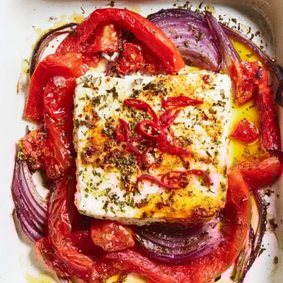 Spicy Baked Feta rests beside fresh parsley and lemon wedges for serving.