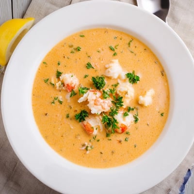 Golden creamy crab and shrimp bisque steaming in a white soup bowl.