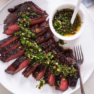 Grilled, sliced Chimichurri Steak Recipe served warm with zesty sauce and char